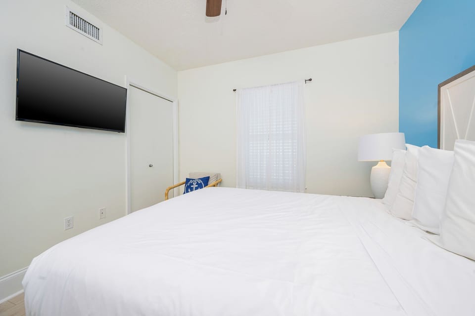 Relax in the guest bedroom featuring a queen bed, a cozy chair, and a large TV for your entertainment