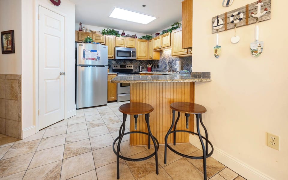 Enjoy casual meals at the kitchen bar, surrounded by warm wood cabinetry and inviting decor