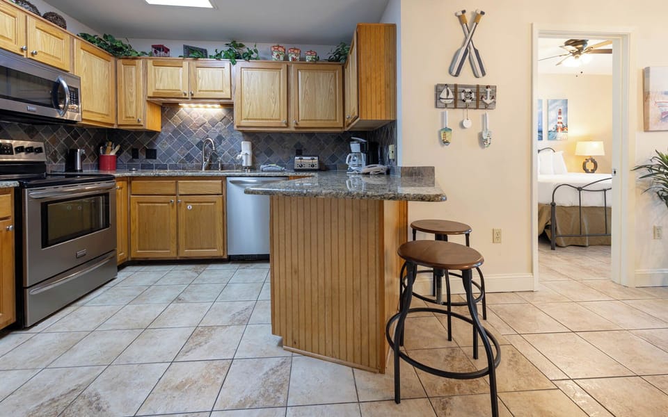 Gather around the kitchen bar for meals, surrounded by charming decor and warm wood cabinetry