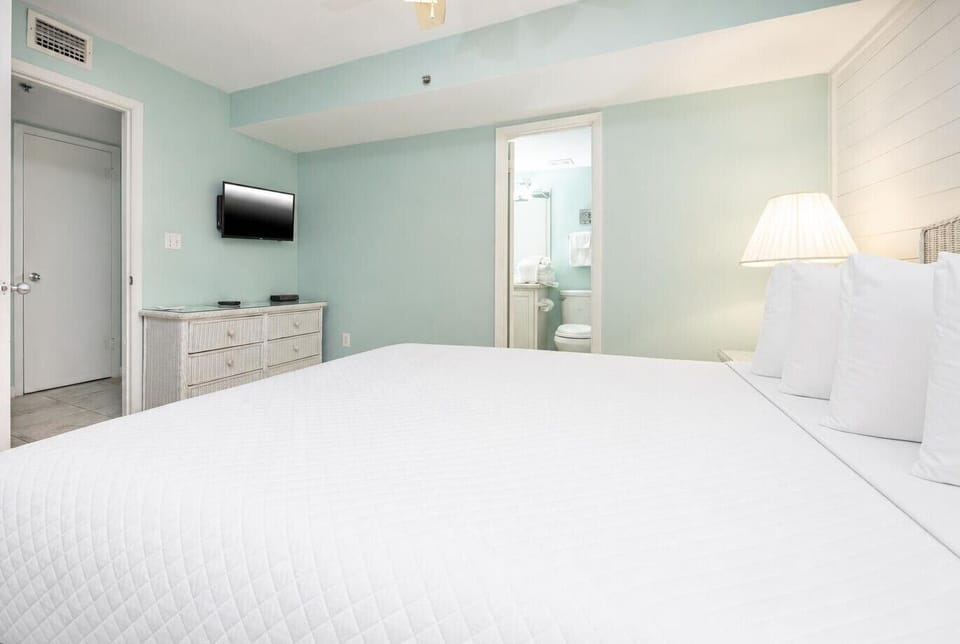 This bedroom features a serene color palette, a flat-screen TV, and an en-suite bathroom for added convenience