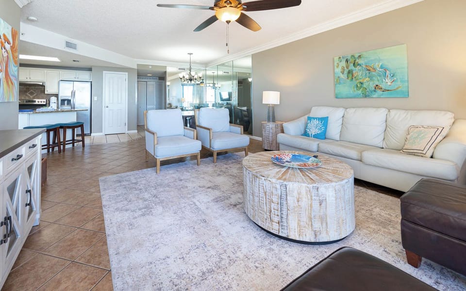 Unwind in the inviting living area with stylish seating, a round coffee table, and vibrant coastal decor