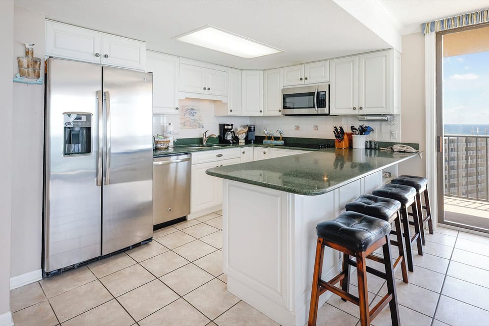 Kitchen featuring white cabinetry, green countertops, and a breakfast bar, offering a view of the beach