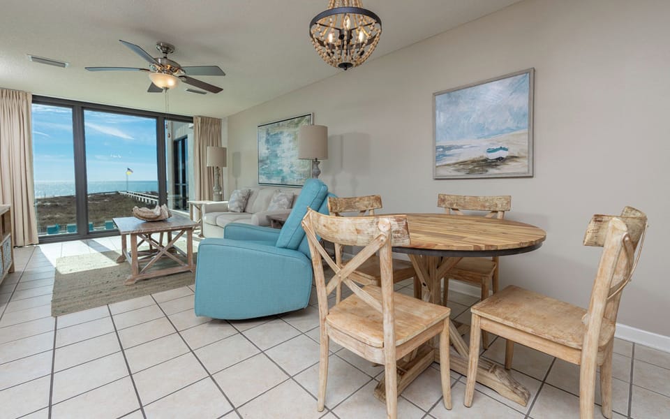 Relax in the inviting living area with a beach view, featuring cozy seating and a rustic dining table for meals together