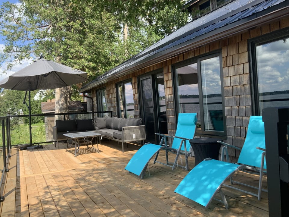 Deck off living room looks over the water. Sectional couch and lounge chairs.