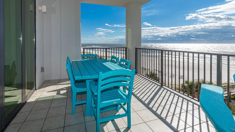 Enjoy dining on the vibrant turquoise patio set while taking in the beachfront and pool area view from this lovely balcony