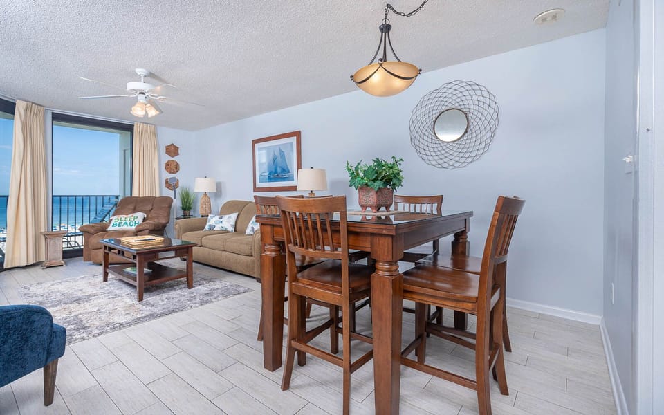 Cozy living area features a comfortable sofa, dining table, and a stunning view of the gulf through large windows