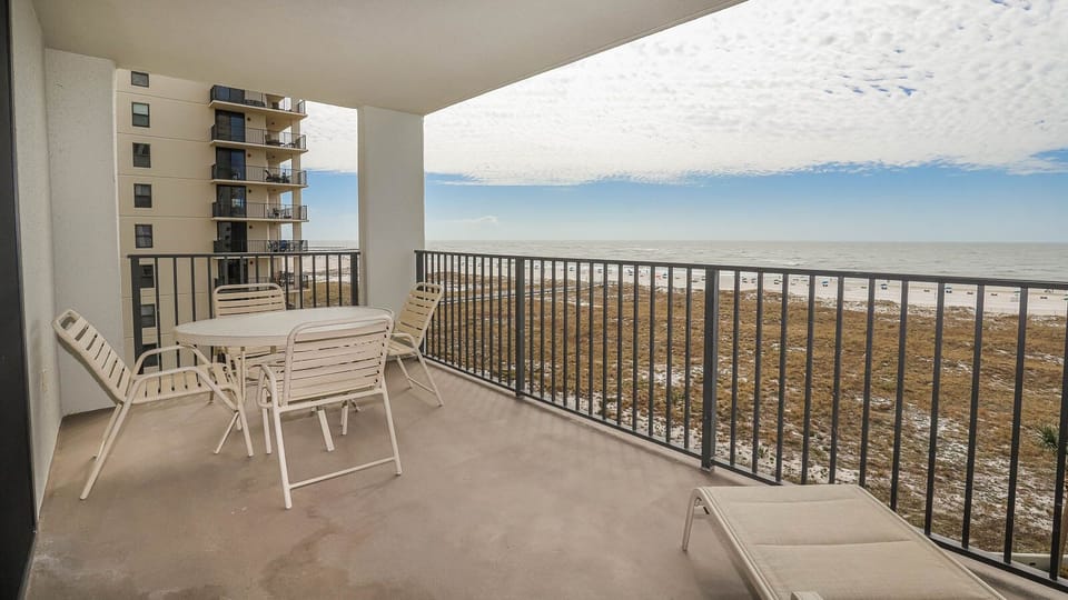Balcony with a table and chairs offers a view of the beach and gulf, perfect for enjoying the coastal breeze