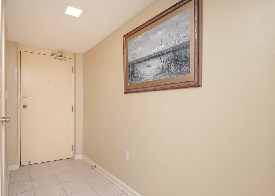 Welcoming entryway featuring a neutral color palette, tile flooring, and a framed coastal artwork enhancing the atmosphere
