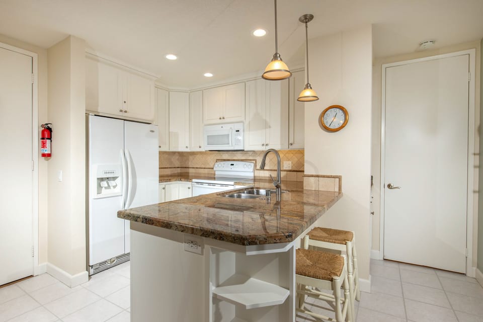 The kitchen has pendant lighting, and two barstools.