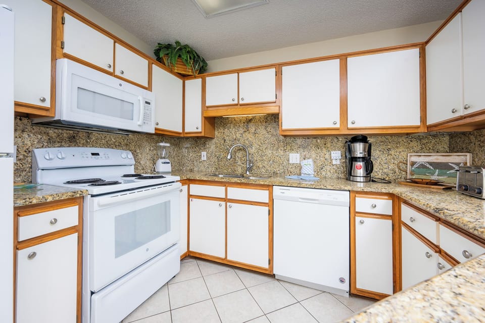 The kitchen features white cabinetry, granite countertops, and modern appliances, perfect for preparing meals