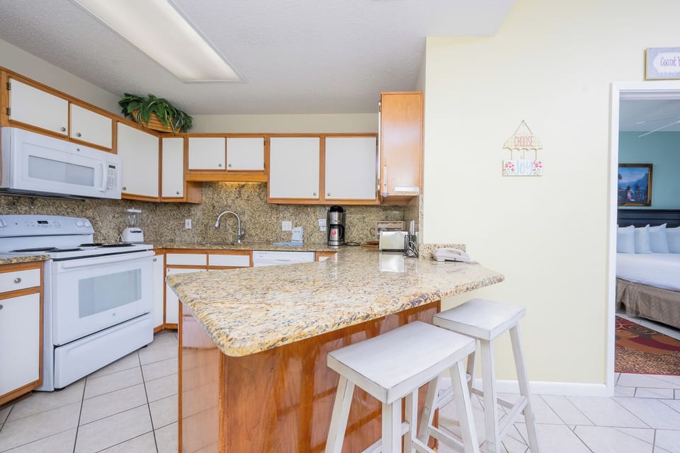 Kitchen features granite countertops, white cabinetry, and a breakfast bar with seating, creating a welcoming atmosphere