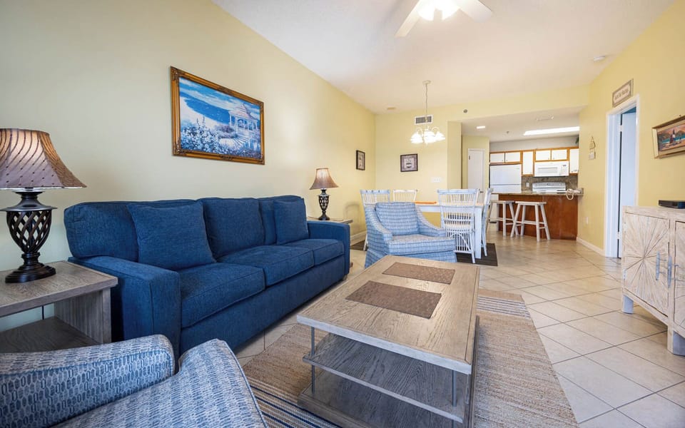 Cozy living area features a blue sofa with queen sleeper, accent chairs, and a dining space, creating a welcoming vibe