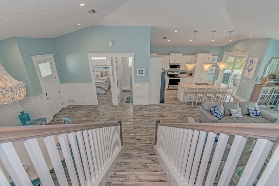 View from stairs over looking the kitchen, dining, living and main floor bedroom
