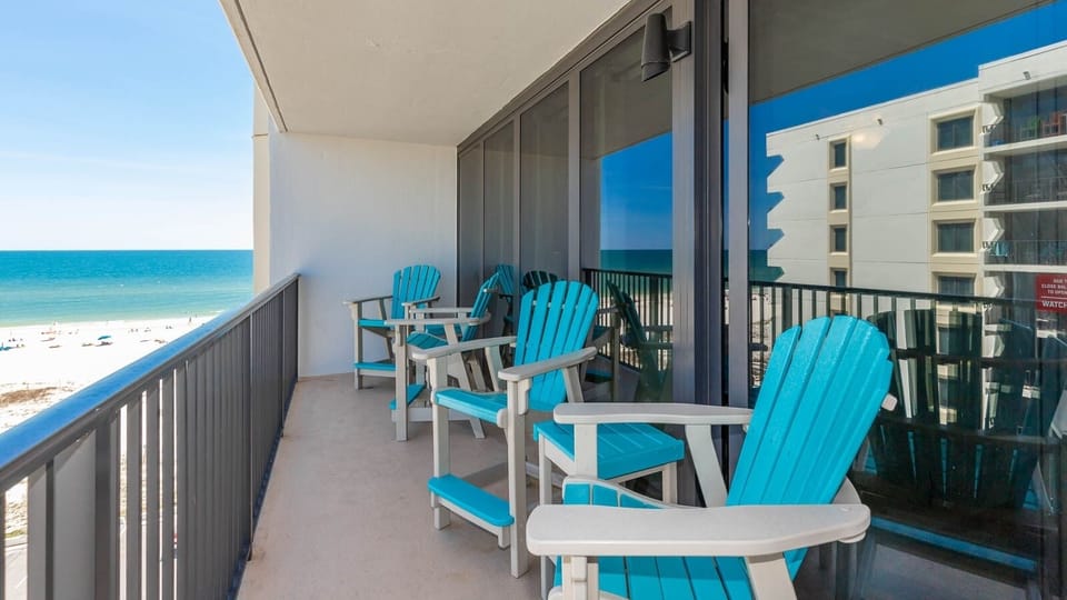 This balcony features bright turquoise chairs, perfect for enjoying a stunning beach view and relaxing moments outdoors