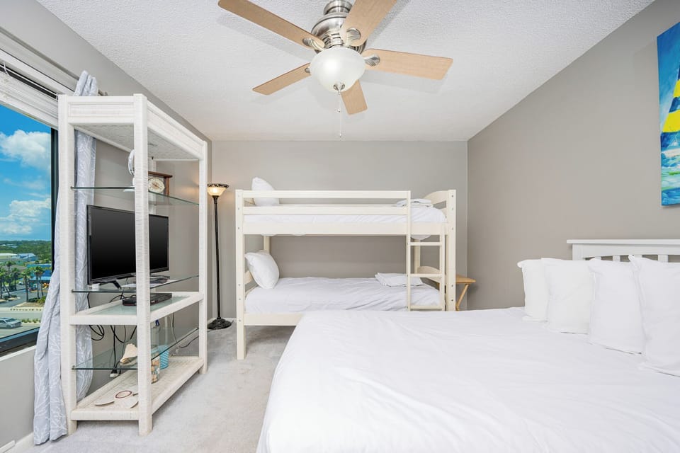 This guest bedroom features a cozy bunk bed, a plush queen bed, and a TV, perfect for family relaxation