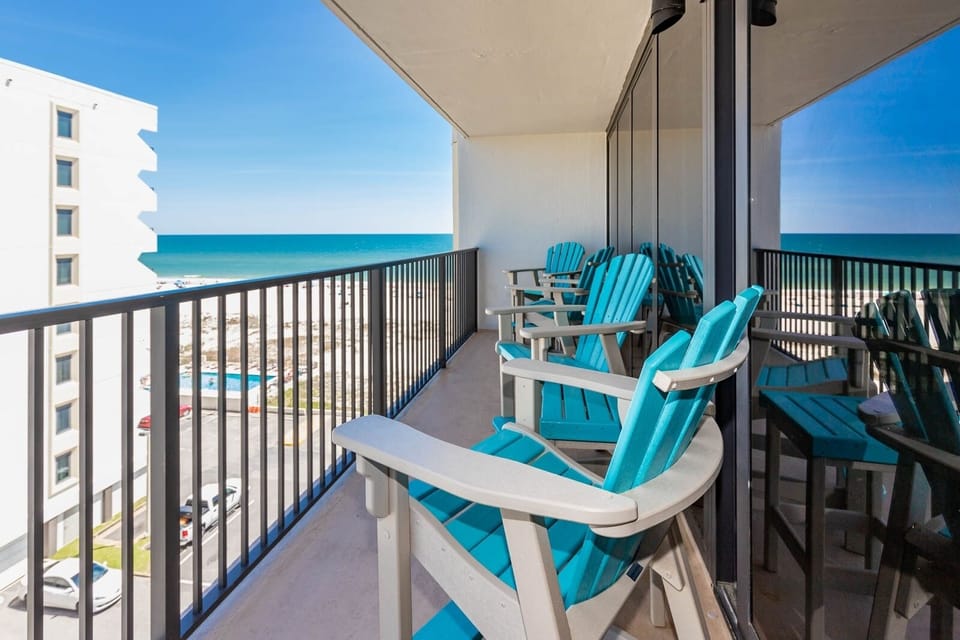 This balcony features bright turquoise chairs with a stunning beach view, perfect for relaxing and enjoying the scenery