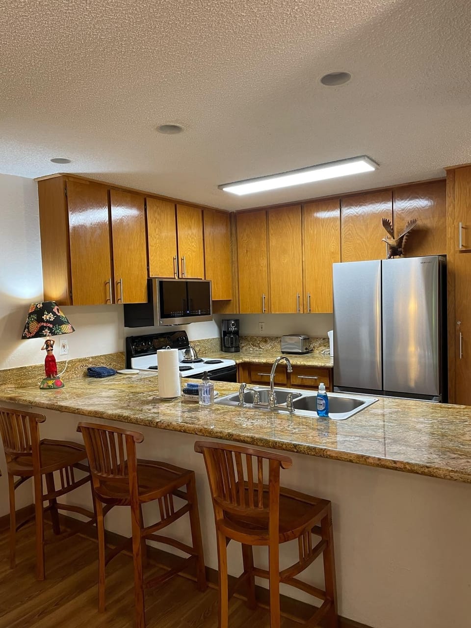 Full kitchen with large granite countertop and bar stools