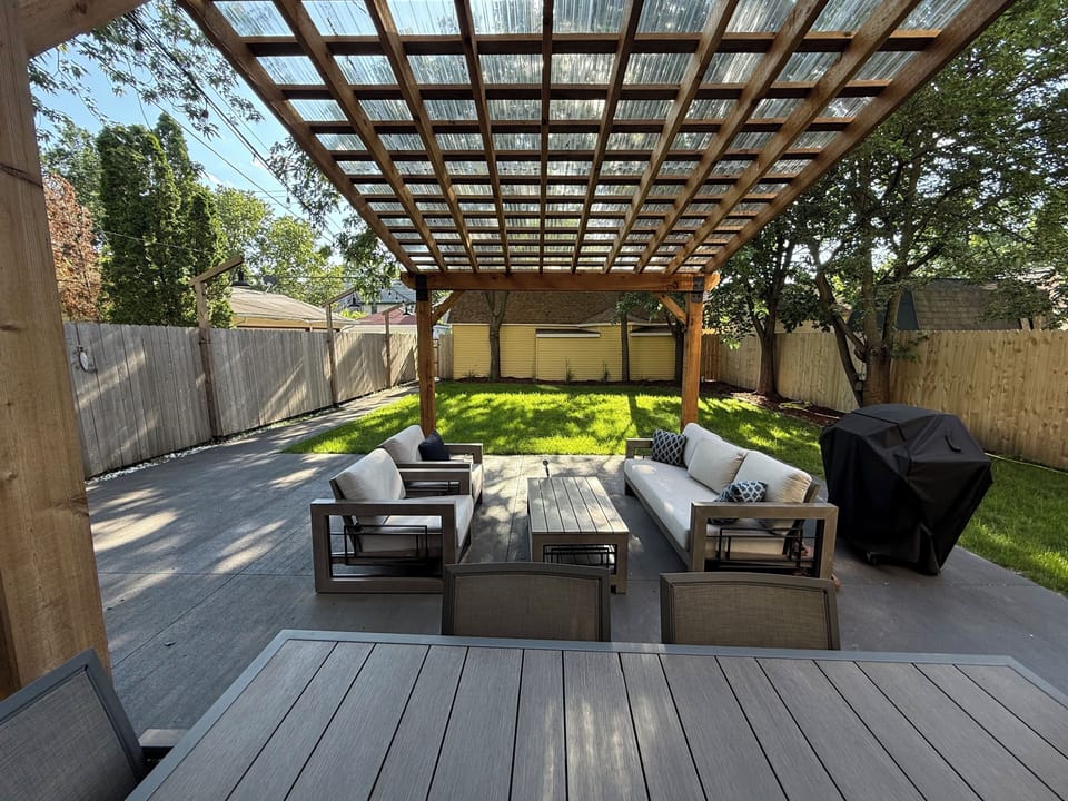 Relax in your private outdoor oasis with comfortable seating under the elegant pergola, overlooking lush green lawn.