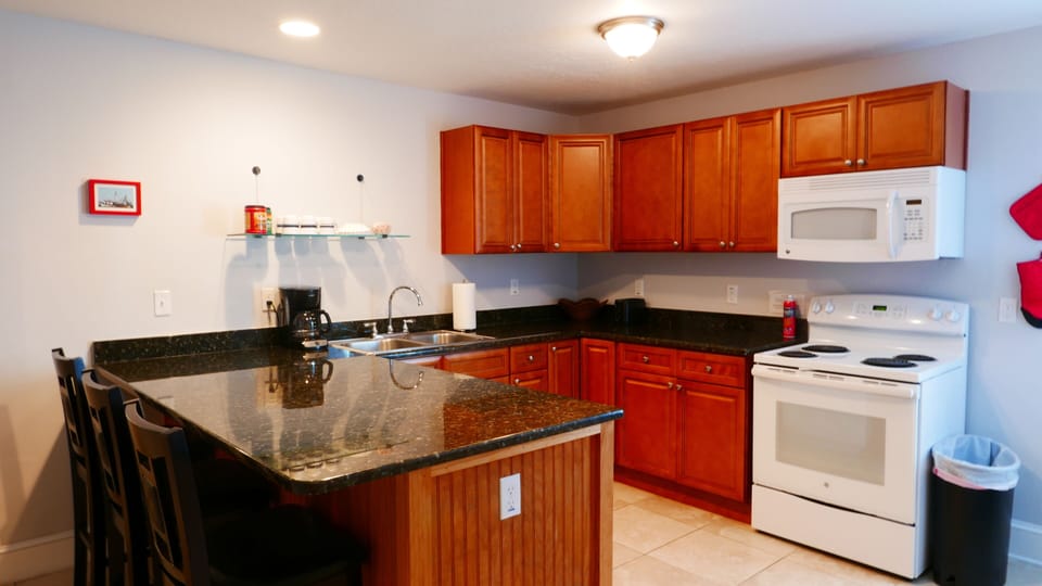 Kitchen with bar chairs, coffee maker, and coffee.