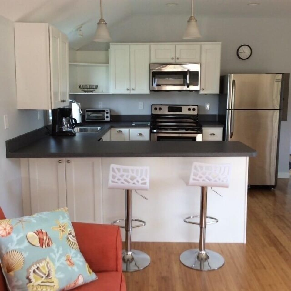 Fully applianced, stainless steel kitchen with breakfast bar and stools.
