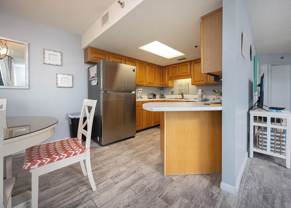 The fully-equipped kitchen features warm wood cabinetry, a breakfast bar with seating, and a cozy dining area for meals