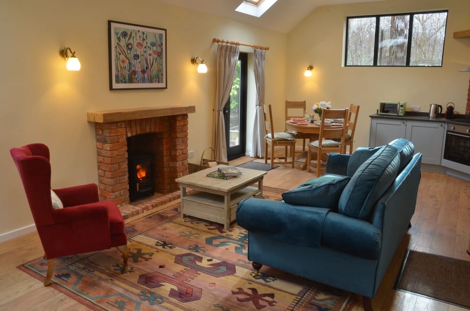 Well lit open plan living room with cosy wood burner.