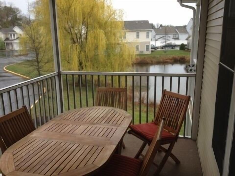 Screened balcony with a teak dining table with views of the pond.
