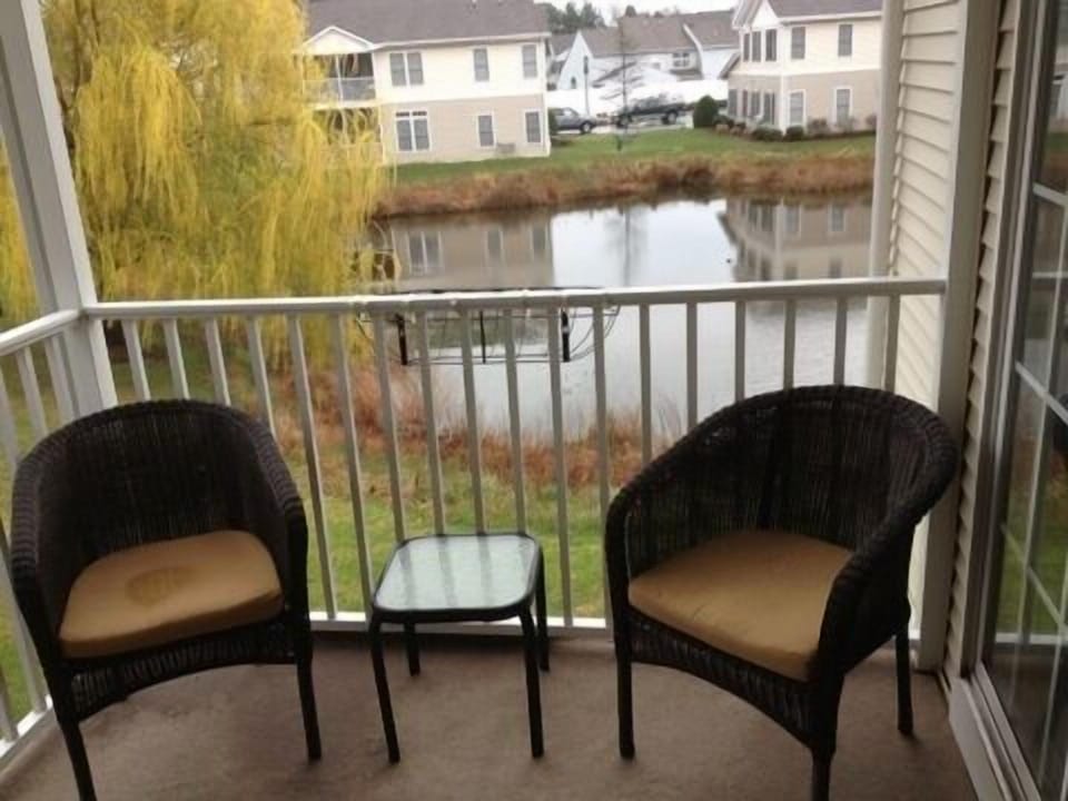 Balcony off master bedroom and great room with four chairs and a small table.