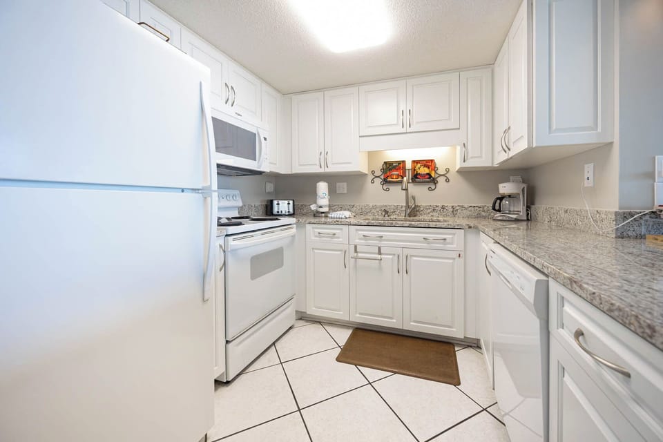 This kitchen features sleek white cabinetry, granite countertops, and modern appliances, perfect for meal preparation