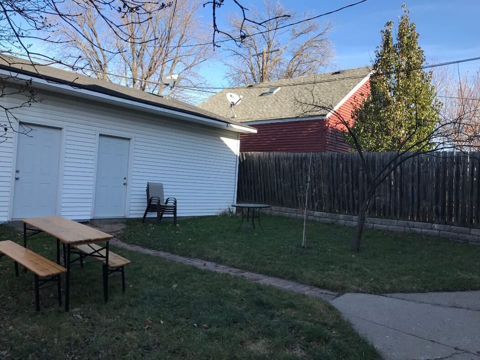 Backyard is fully fenced in for privacy, with seating and charcoal grill.