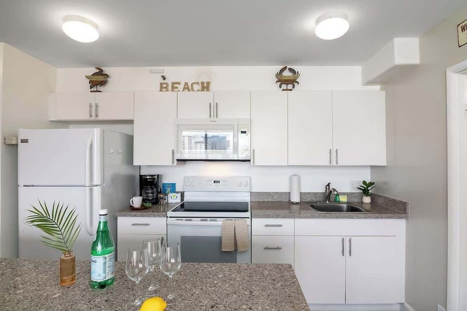 Prepare your vacation refreshments in this clean, well-equipped kitchen featuring modern white cabinets, appliances, and cute decors.