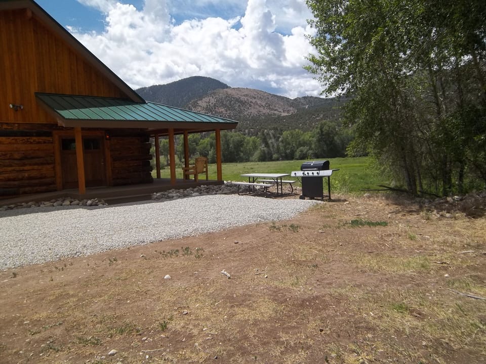 West side of cabin with wrap around deck with a view of the mountains.