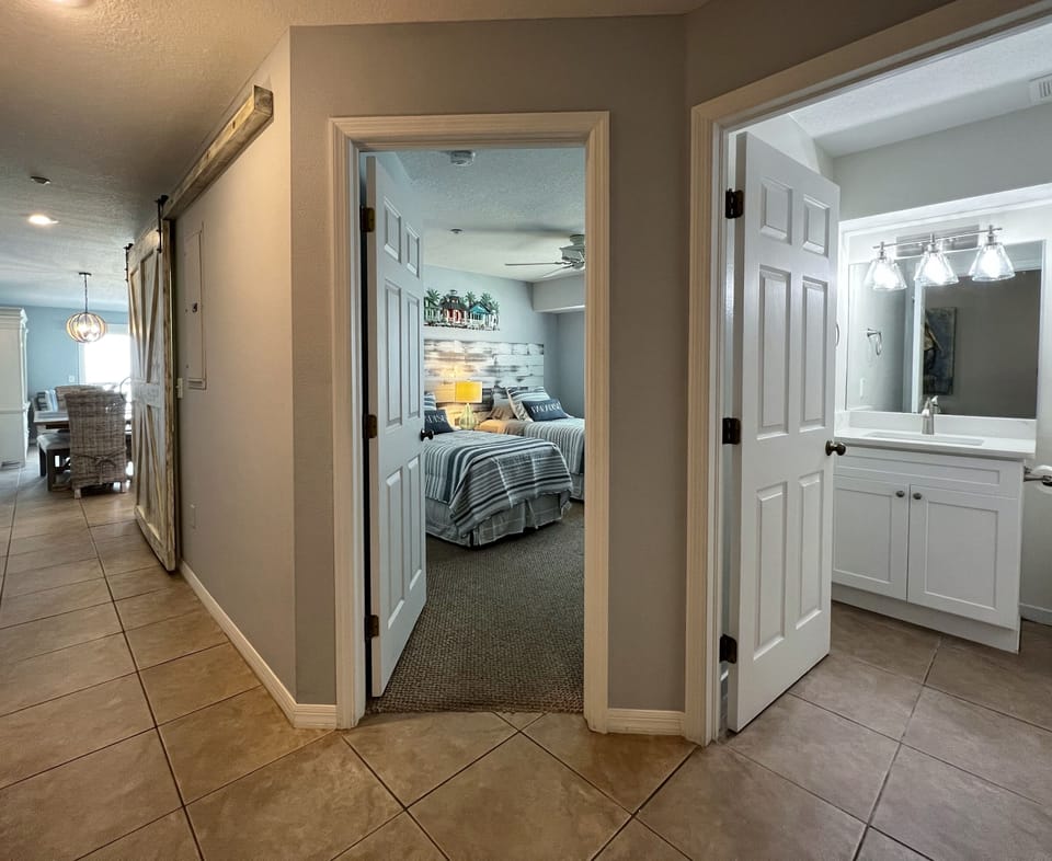 Hallway to guest bathroom, guest bedroom, and main living area w - Hallway to guest bathroom, guest bedroom, and main living area with a beachfront view.