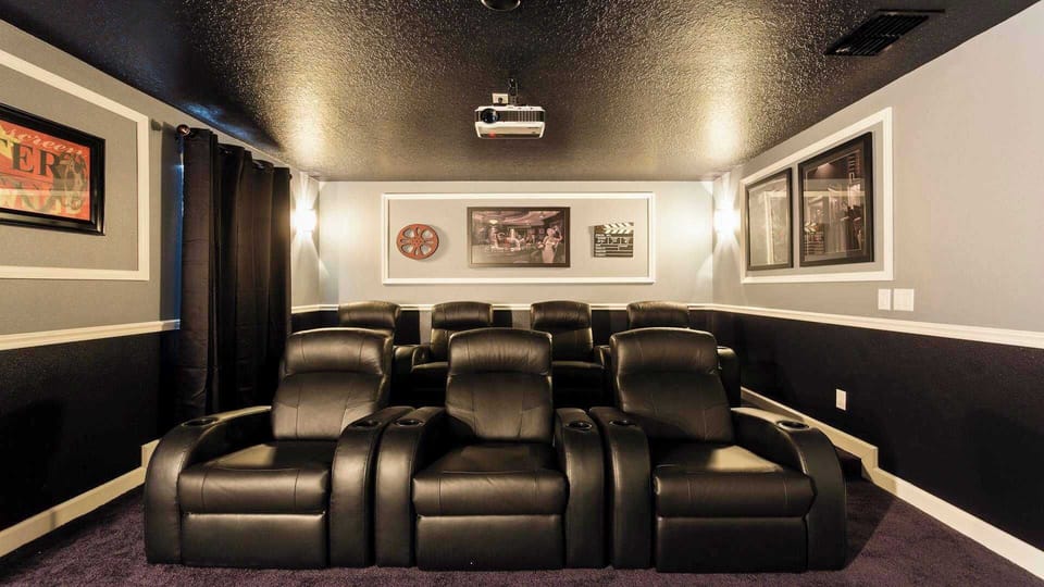 Luxurious home theater featuring plush leather recliners, ambient lighting, and classic cinema decor.