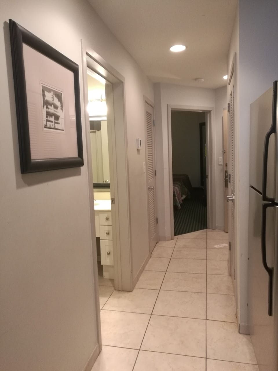Bright tiled hallway with access to bedroom, bathroom, and kitchen.