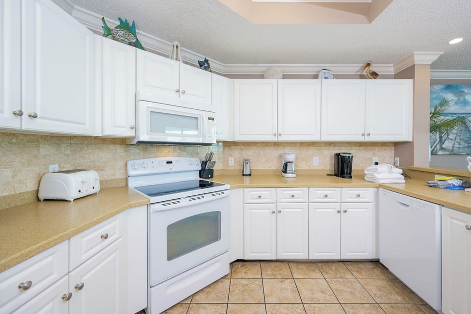 Prepare meals in this kitchen with sleek cabinetry, white appliances, and spacious countertops