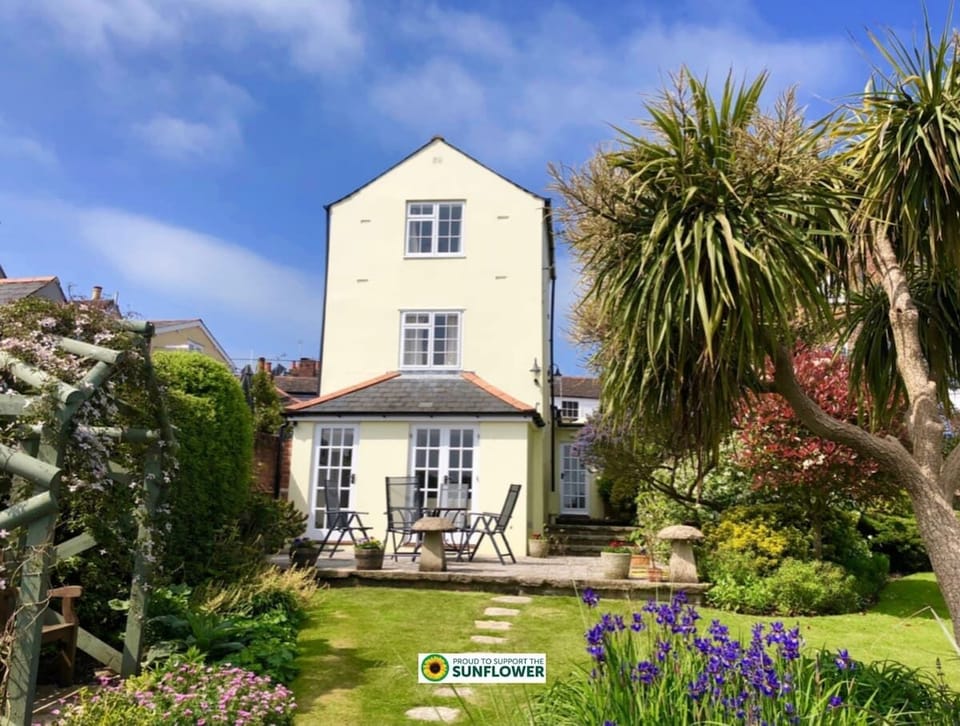 Front exterior of Mulberry Cottage, a coastal holiday home in Cowes with entrance, seating area and pretty façade.
