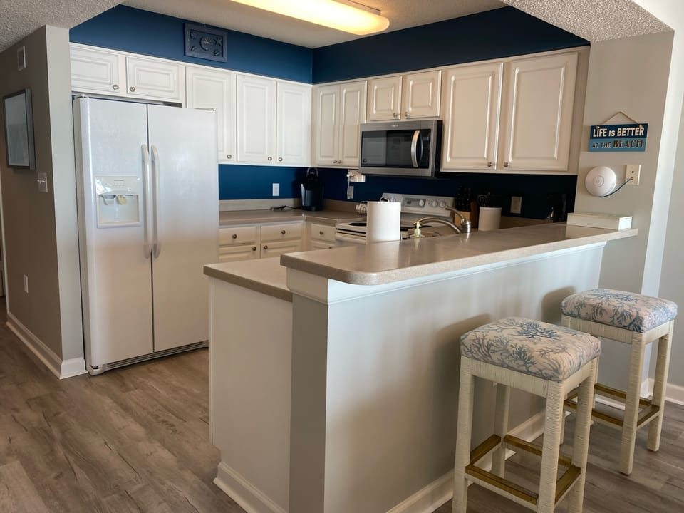 Kitchen with new microwave and new floors. Seating at the bar for two.