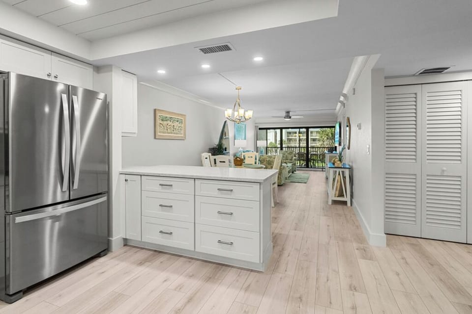 Bright coastal kitchen with white cabinetry, stainless steel appliances, and a sleek blue tile backsplash.