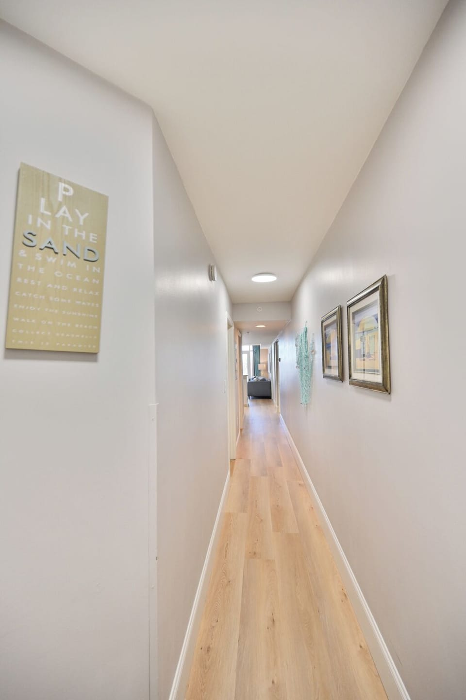 A simple, well-lit hallway with light wood flooring, leading to multiple rooms, 