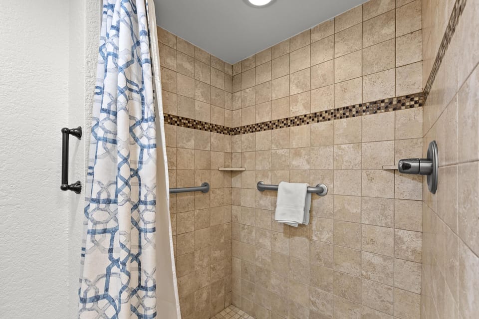 Spacious tiled shower with modern fixtures and elegant accents