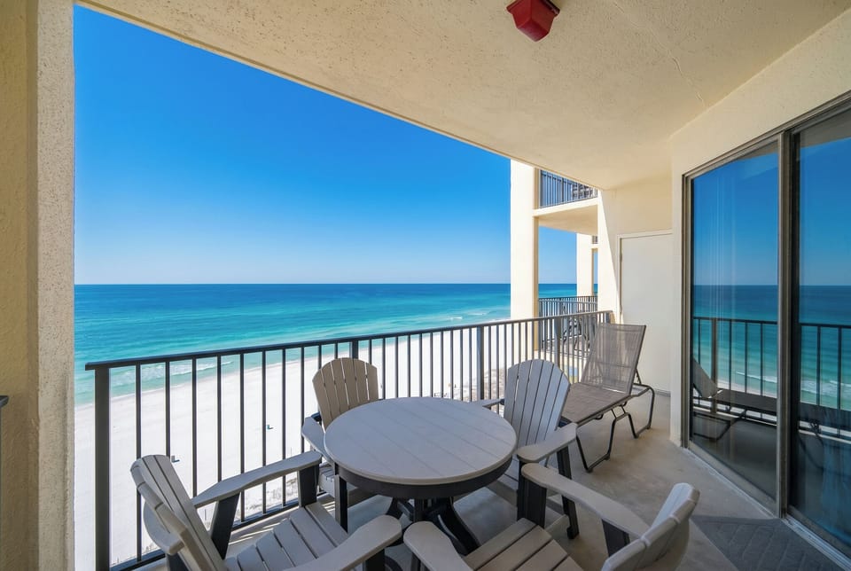 Relax on the balcony with a table and chairs, overlooking the white sand beach and tranquil waters