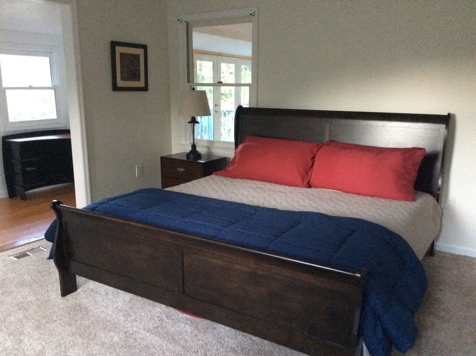 Master bedroom. There is a shade on the window next to the bed.
