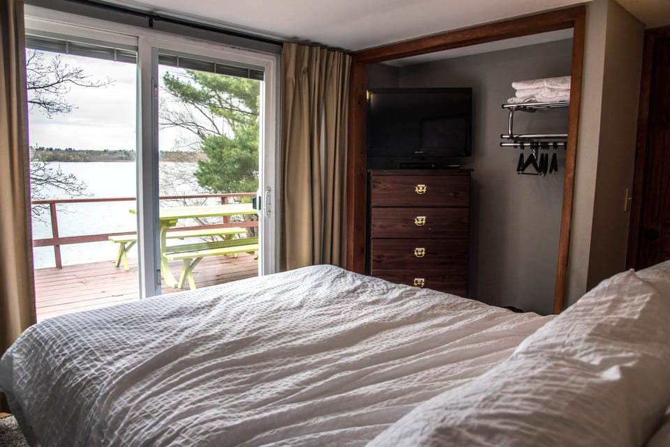 A queen bed and sliding glass door leading out to the deck overlooking the lake