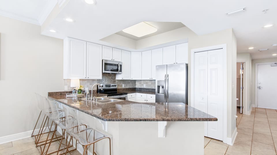 Fully equipped kitchen with granite, bar seating and stainless steel appliances.