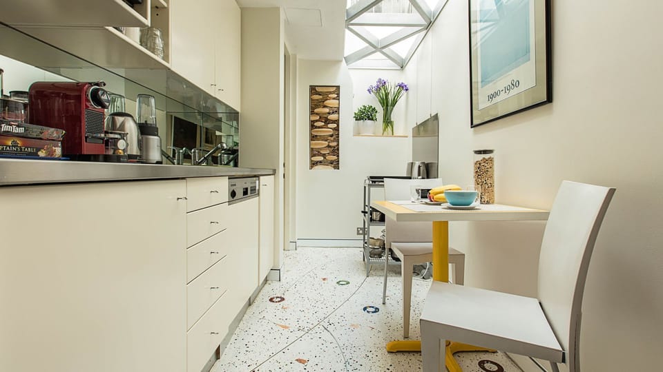 Modern galley style kitchen and table for 2 under a glass sky roof.