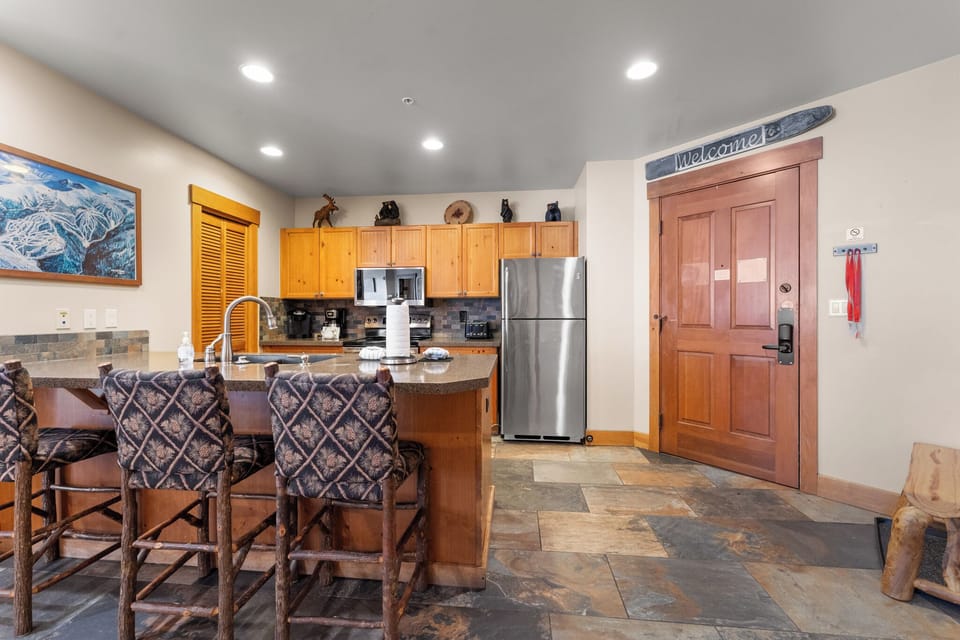 Your mountain retreat kitchen invites gathering with warm wood cabinets, granite breakfast bar, and stainless appliances for memorable meals.