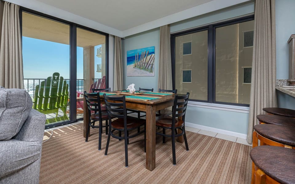 This inviting dining area features a wooden table, stylish black chairs, and a breathtaking view from the balcony