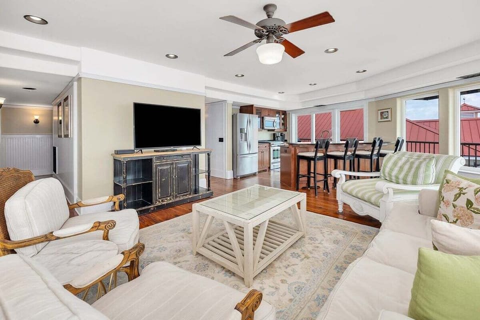 Living room with white sofa, flat-screen TV, and ceiling fan