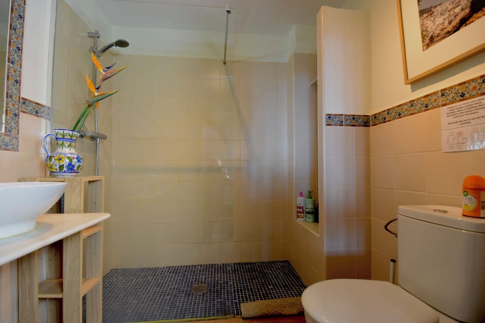 Connecting bathroom with a walk-in double shower, single sink and toilet